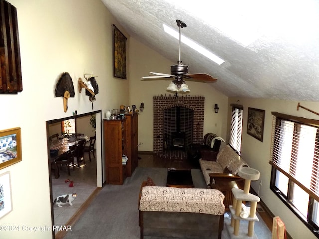 living room with vaulted ceiling, a wood stove, ceiling fan, and a textured ceiling