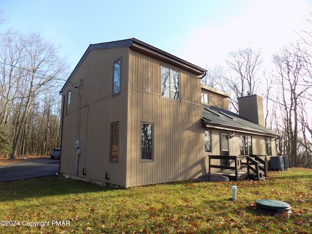 view of side of property featuring central air condition unit and a lawn