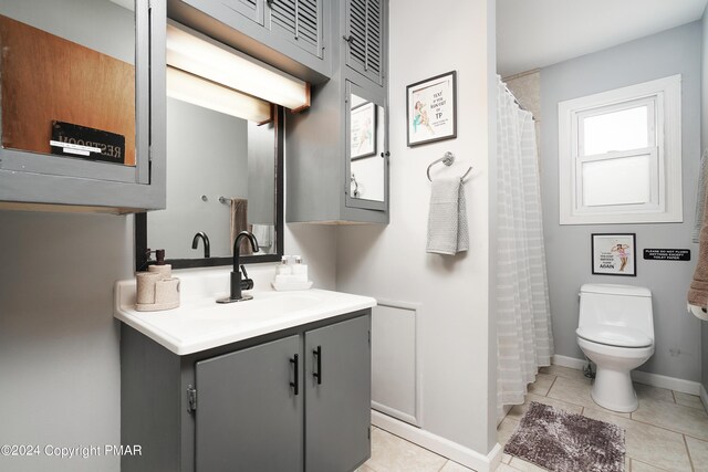 bathroom featuring baseboards, vanity, toilet, and tile patterned floors