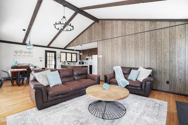 living area with an inviting chandelier, light wood-style flooring, wooden walls, and beamed ceiling