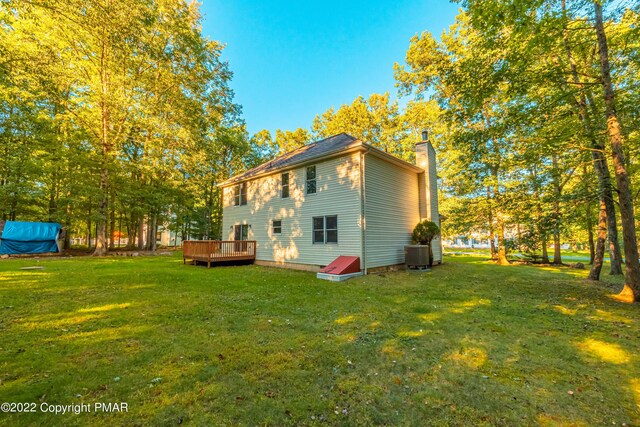 rear view of property with central AC unit, a deck, and a lawn