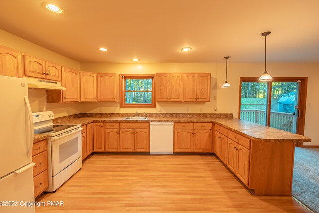 kitchen featuring light brown cabinetry, hanging light fixtures, and white appliances