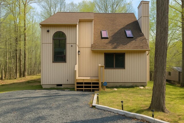 view of front of home with a front lawn, roof with shingles, and a chimney