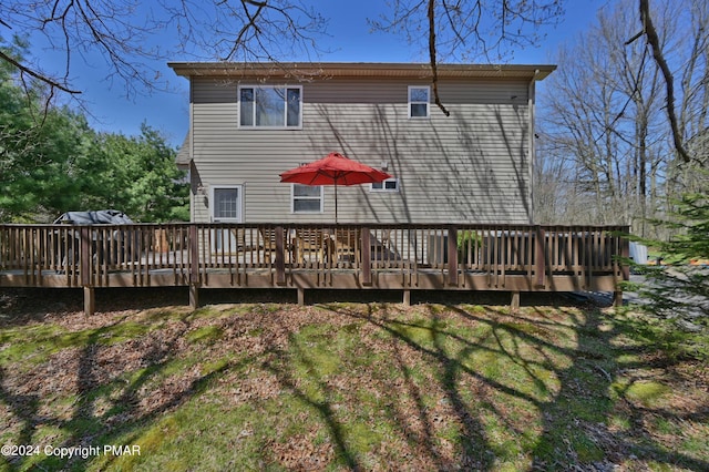 back of property with a wooden deck and a lawn