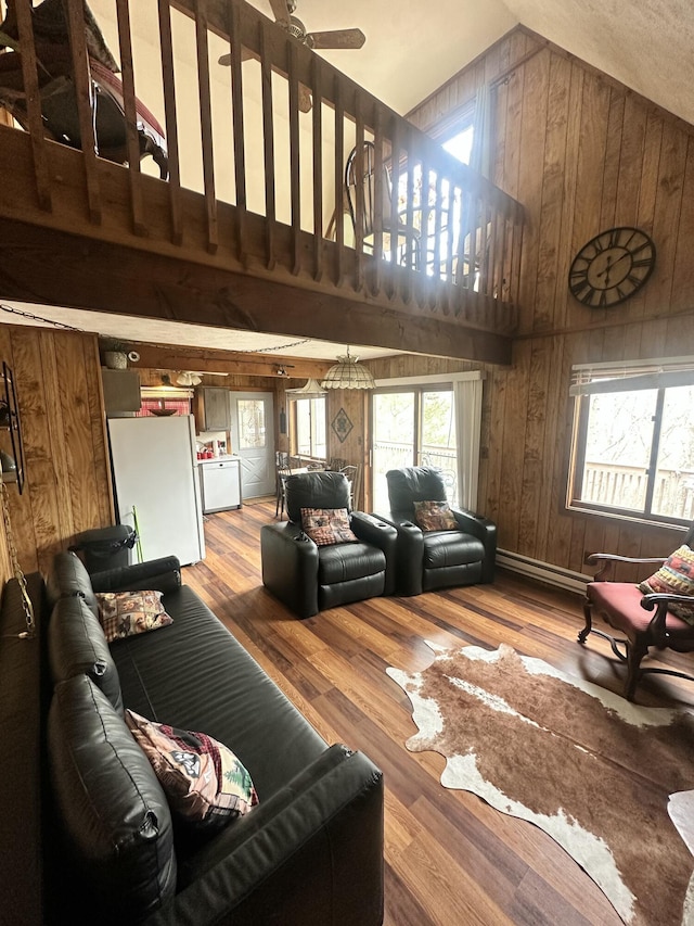 living room with high vaulted ceiling, plenty of natural light, and wood walls