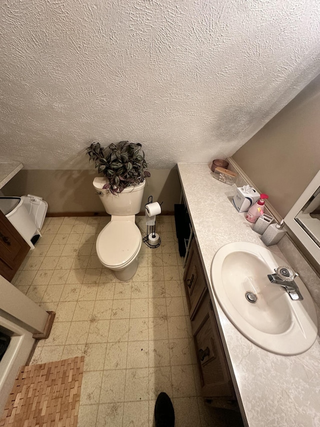 bathroom with tile patterned floors, vanity, a textured ceiling, and toilet