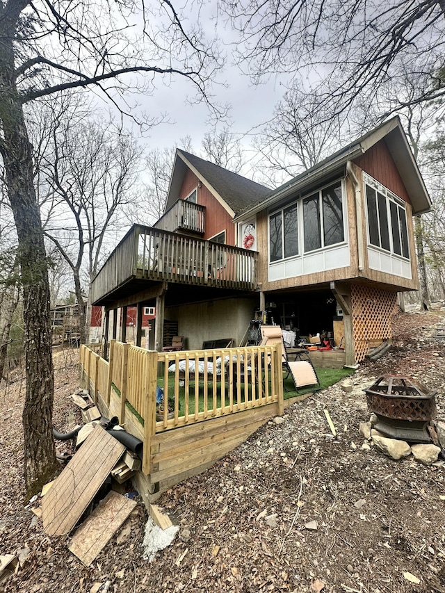 back of house featuring a wooden deck and a fire pit