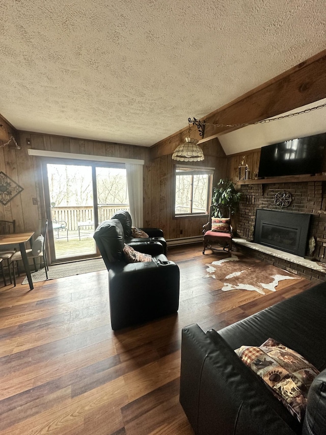living area featuring wood walls, a brick fireplace, a textured ceiling, and hardwood / wood-style floors