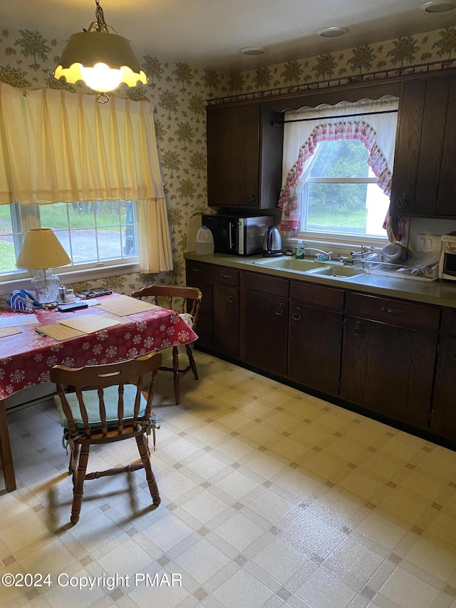 kitchen featuring light floors, dark brown cabinetry, a sink, black microwave, and wallpapered walls