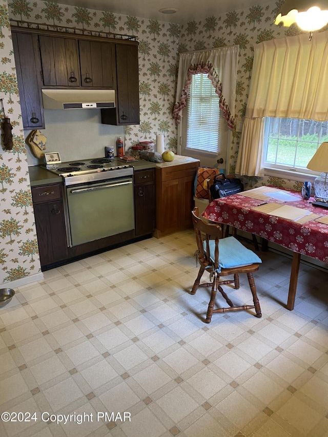 kitchen featuring under cabinet range hood, baseboards, electric stove, light floors, and wallpapered walls