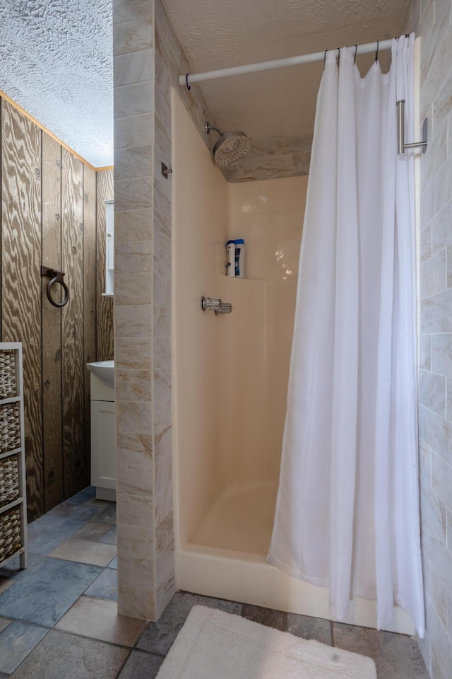 bathroom with a shower stall, stone tile floors, and vanity