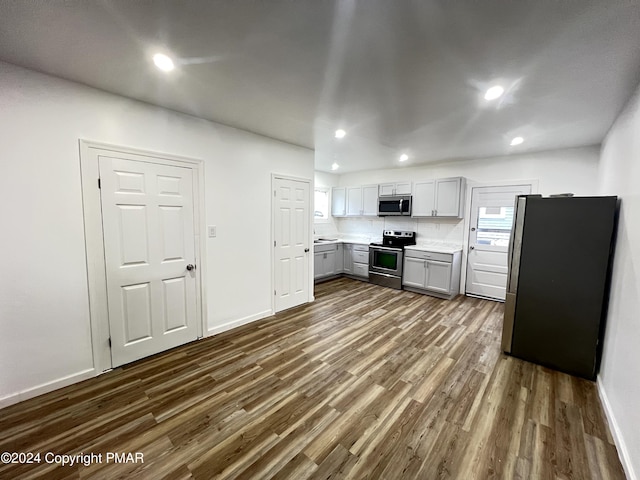 kitchen featuring recessed lighting, gray cabinets, light countertops, appliances with stainless steel finishes, and dark wood-type flooring