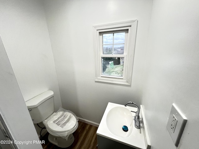 half bathroom with baseboards, vanity, toilet, and wood finished floors