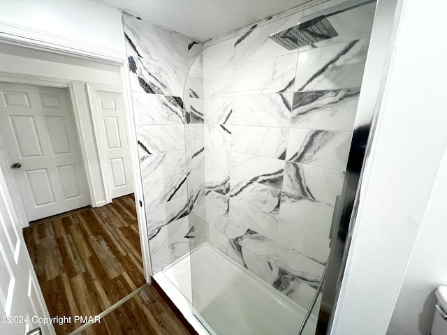 bathroom featuring wood finished floors, walk in shower, and toilet