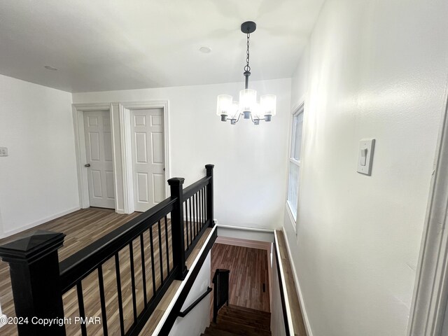 stairway featuring a chandelier, wood finished floors, and baseboards