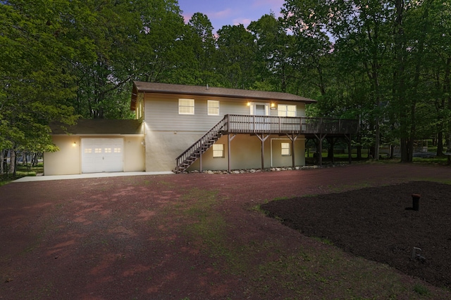 289 Towamensing Trl, Albrightsville, PA 18210 - view of front of house with dirt driveway, a garage, a wooden deck, stairs, and stucco siding