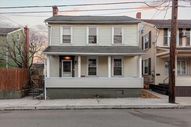 view of front facade featuring a porch, a chimney, and fence