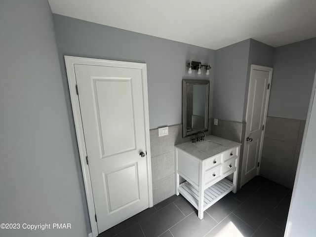 bathroom with vanity, wainscoting, tile patterned flooring, and tile walls