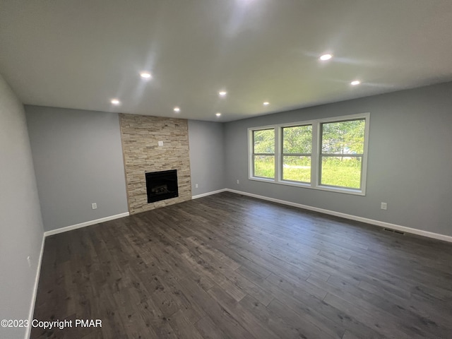 unfurnished living room featuring visible vents, baseboards, dark wood-style floors, a fireplace, and recessed lighting