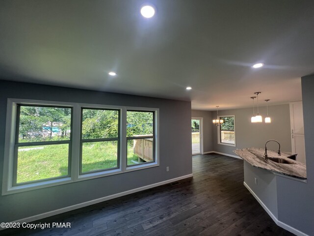 interior space featuring recessed lighting, a sink, baseboards, light stone countertops, and dark wood finished floors