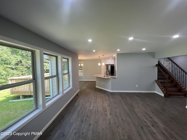 unfurnished living room with dark wood-style floors, recessed lighting, baseboards, and stairs