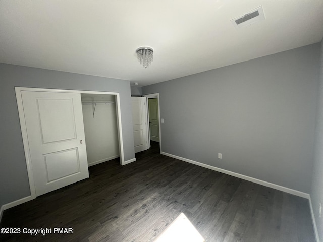 unfurnished bedroom featuring dark wood-style flooring, visible vents, and baseboards