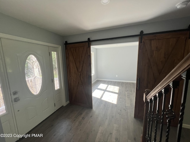 foyer featuring wood finished floors, stairway, baseboards, and a barn door