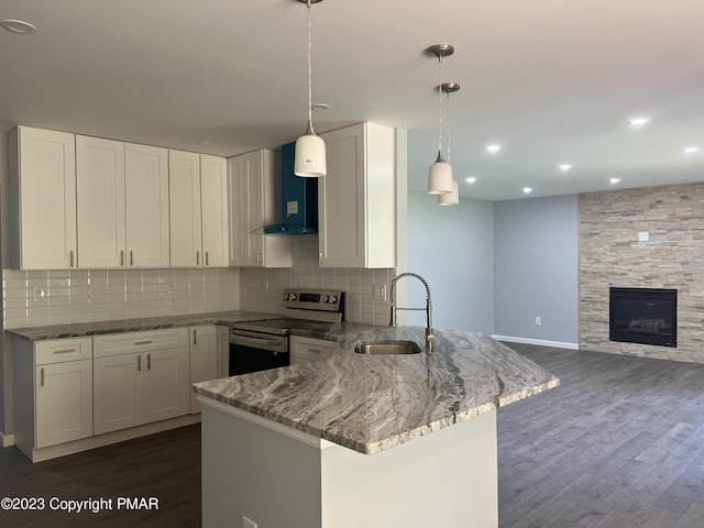 kitchen with electric range, a sink, wall chimney range hood, dark stone countertops, and a peninsula