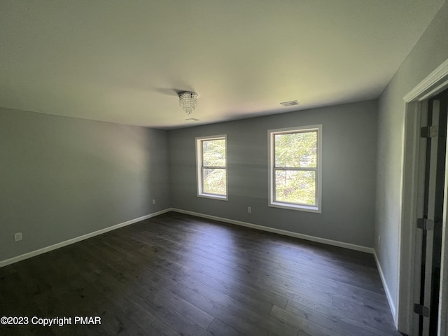 unfurnished room featuring dark wood-style floors, baseboards, and visible vents