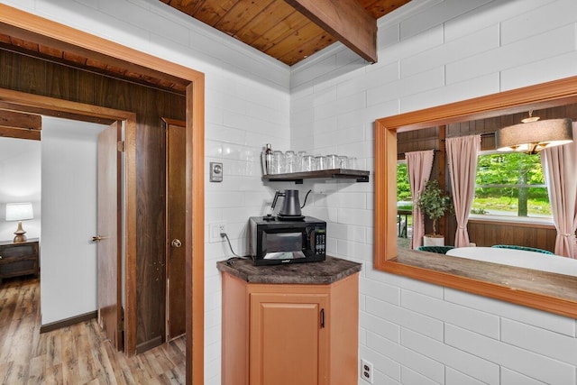 322 Clubhouse Dr, East Stroudsburg, PA 18302 - kitchen featuring black microwave, light wood-style floors, wooden ceiling with exposed beams, dark countertops, and a wood stove