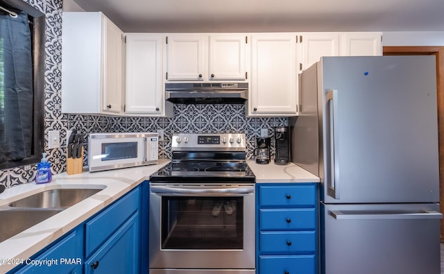 kitchen featuring under cabinet range hood, blue cabinetry, backsplash, white cabinetry, and stainless steel appliances