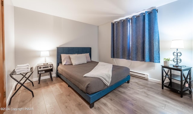 bedroom featuring wood finished floors, baseboards, and baseboard heating