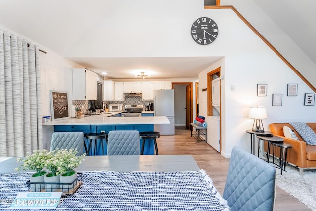 kitchen with electric stove, backsplash, freestanding refrigerator, a peninsula, and white cabinets