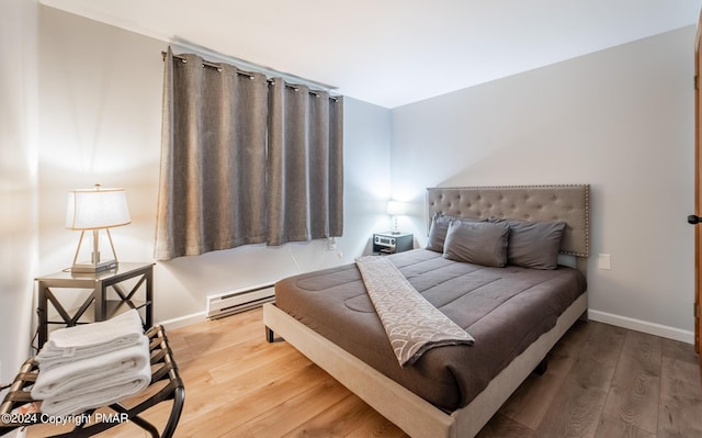 bedroom featuring baseboards, baseboard heating, and wood finished floors