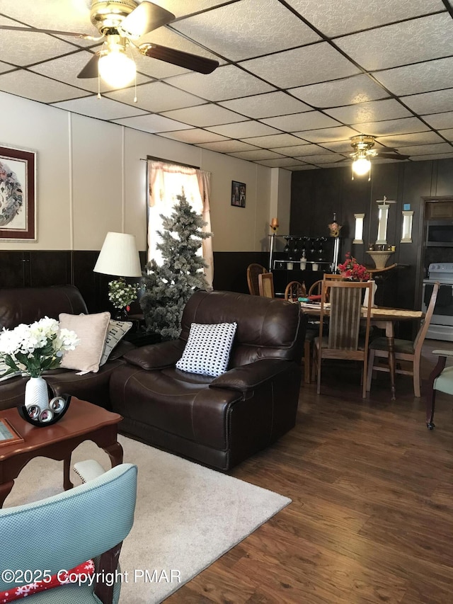 living room featuring hardwood / wood-style flooring, a drop ceiling, and ceiling fan