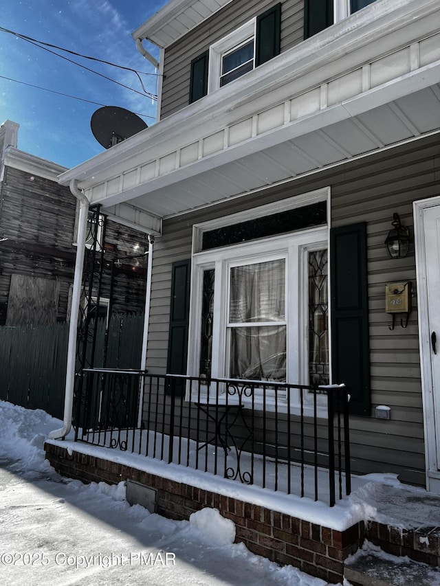 snow covered property entrance with a porch