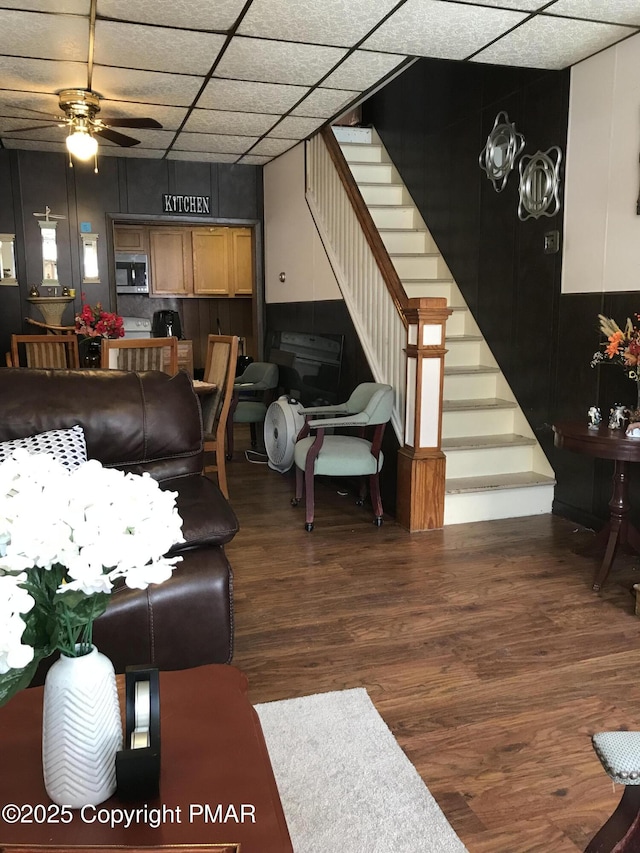 living room featuring ceiling fan, a paneled ceiling, and dark hardwood / wood-style floors