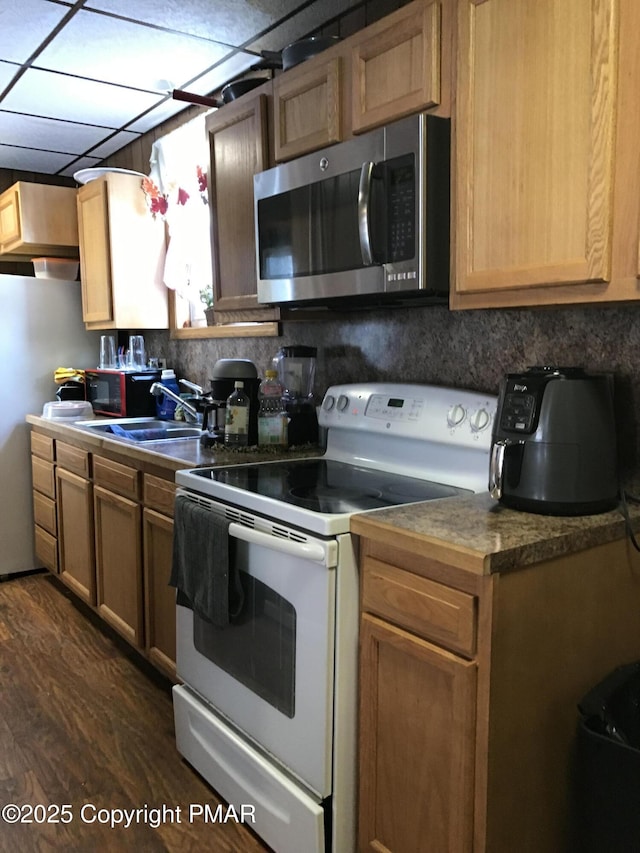 kitchen featuring appliances with stainless steel finishes, dark hardwood / wood-style floors, a paneled ceiling, sink, and decorative backsplash