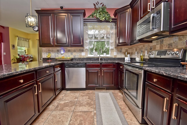 603 Washington Xing, East Stroudsburg, PA 18301 - kitchen with stainless steel appliances, decorative backsplash, reddish brown cabinets, a chandelier, and decorative light fixtures