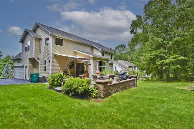 603 Washington Xing, East Stroudsburg, PA 18301 - back of house featuring a yard, a garage, asphalt driveway, and a patio area