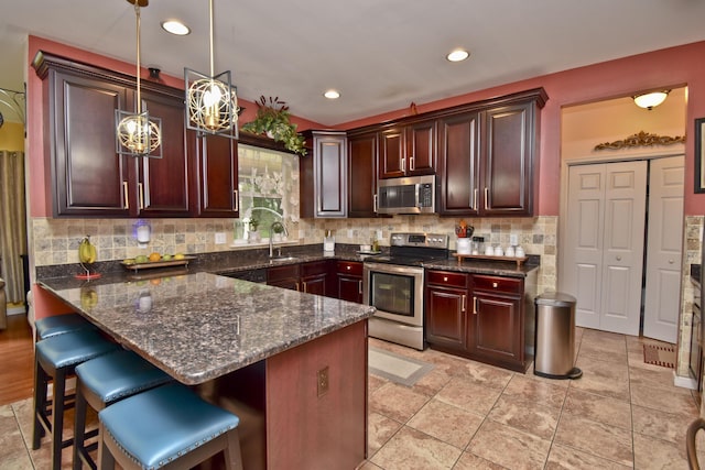 603 Washington Xing, East Stroudsburg, PA 18301 - kitchen with stainless steel appliances, hanging light fixtures, a peninsula, decorative backsplash, and a breakfast bar area