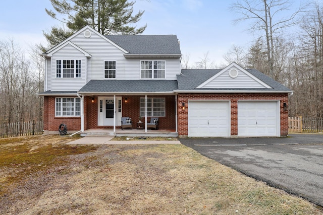 traditional home featuring covered porch, driveway, a shingled roof, and an attached garage