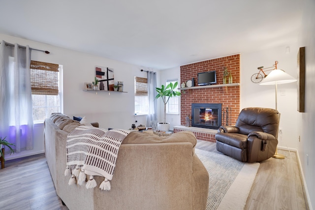 living room featuring a healthy amount of sunlight, a fireplace, baseboards, and wood finished floors