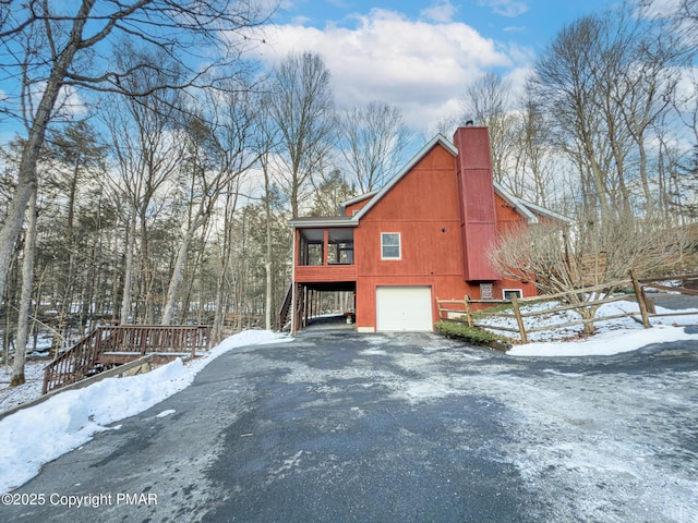 view of snow covered exterior featuring a garage and a sunroom