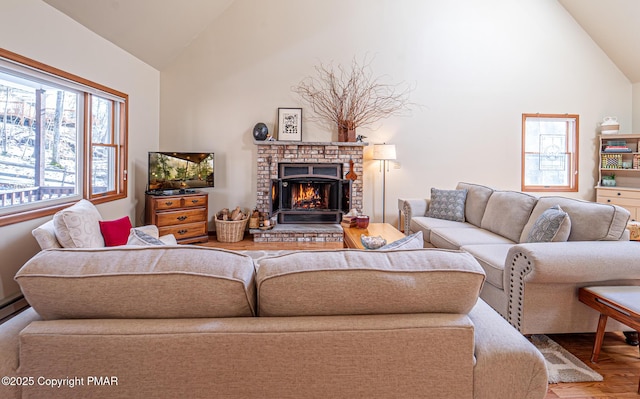 living room with wood-type flooring, high vaulted ceiling, and a brick fireplace