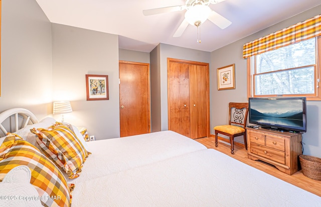 bedroom with ceiling fan, wood-type flooring, and multiple closets