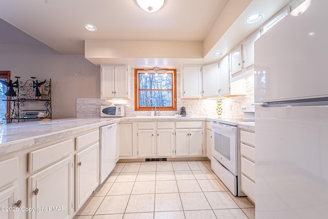 kitchen featuring white cabinetry, sink, decorative backsplash, light tile patterned floors, and white appliances