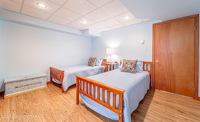 bedroom featuring light hardwood / wood-style floors and a drop ceiling