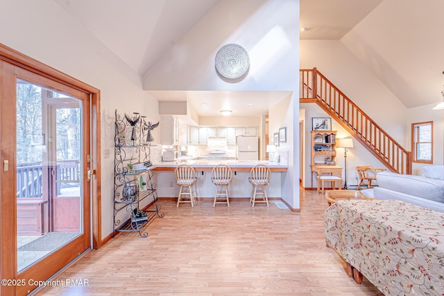 living room featuring high vaulted ceiling and light hardwood / wood-style flooring