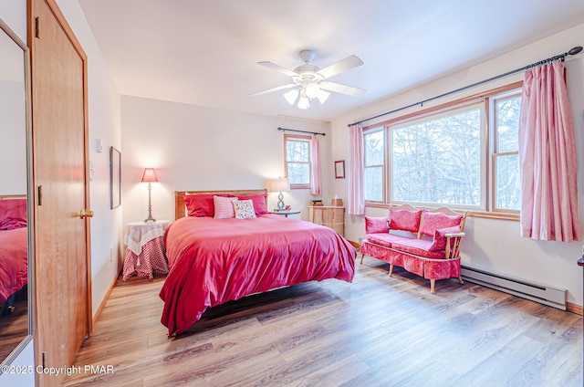 bedroom featuring light wood-type flooring, ceiling fan, and baseboard heating